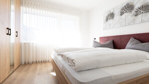A bedroom with a wooden floor, a bed with white bedding, a red headboard, and a wall-mounted artwork. - Holiday Apartment "Kleon 3" with Mountain View, Shared Pool and Wi-Fi (Riffian)