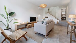 Ein modernes Wohnzimmer mit einer Couch, einem Fernseher, einer Pflanze und einer Treppe zu einer weiteren Ebene.
