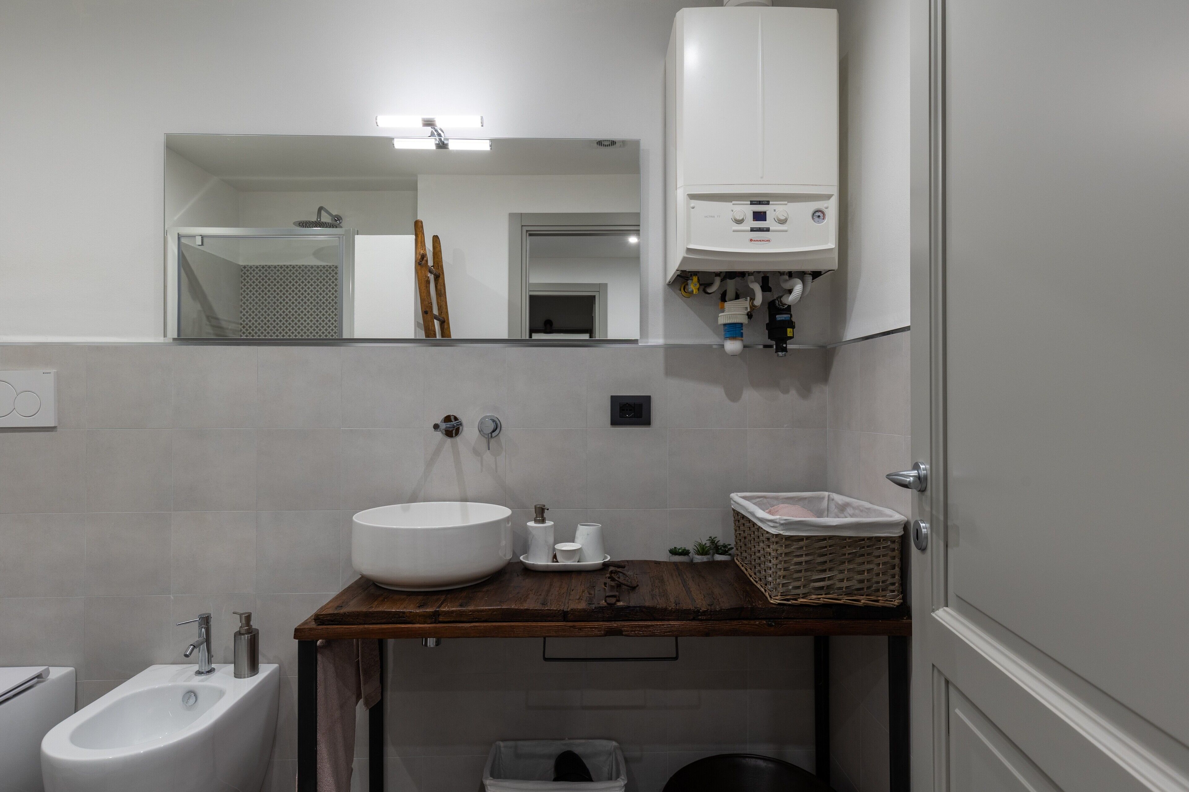 Een badkamer met een grote wastafel, een bidet, een spiegel, een handdoekhouder en een toiletrolhouder.