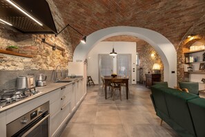 Une cuisine avec un mur en briques, des appareils modernes et une porte en arc donnant sur un coin repas.