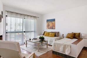 Una habitación con una cama, un sofá, una mesa con una planta y un cuadro en la pared.
