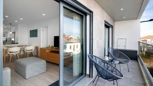 Et moderne interiør med et spiseområde, et køkken og en balkon med stole.