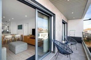 A modern interior with a dining area, a kitchen, and a balcony with chairs.