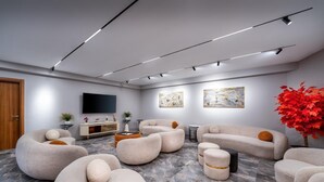 Een moderne woonkamer met een grote flatscreen televisie, comfortabele banken en een grote potplant.