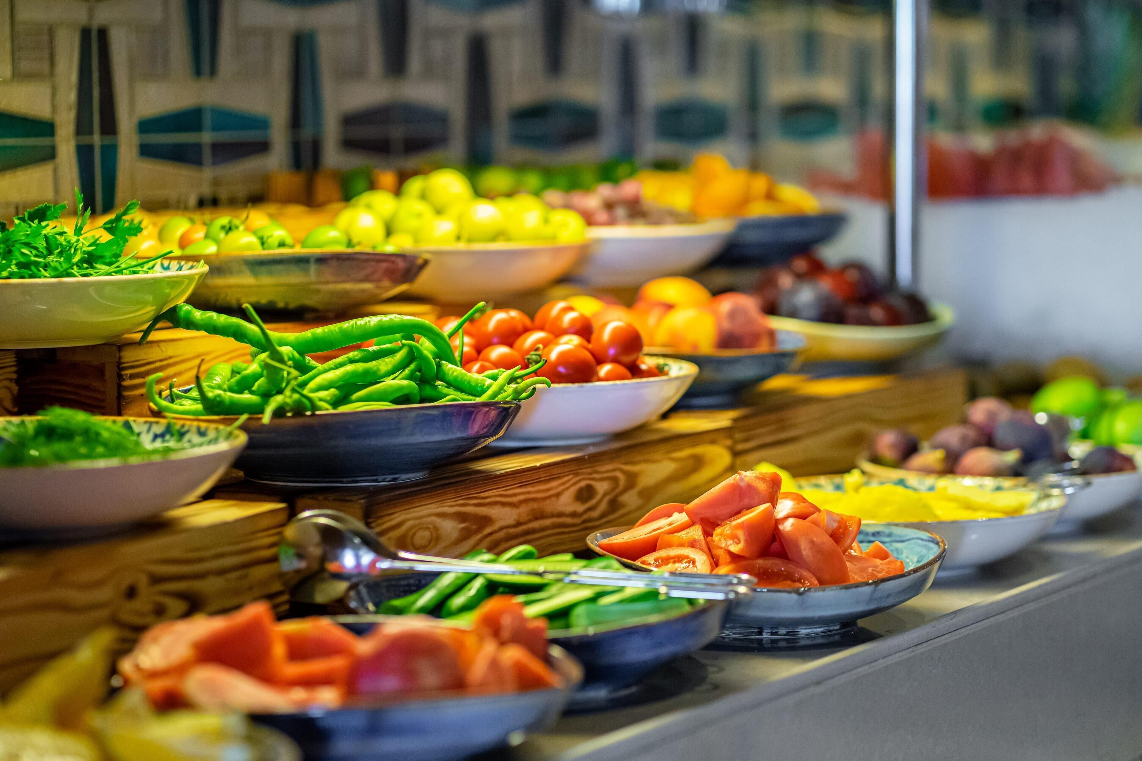 A buffet with various food items including vegetables, fruits, and meats.