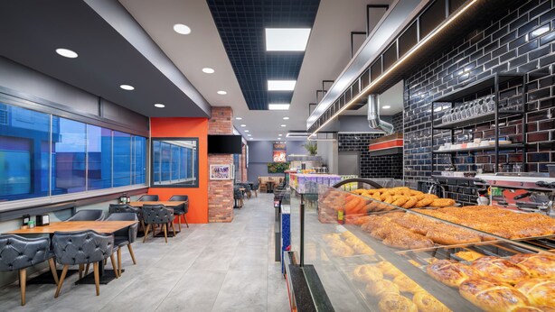 Een moderne café met een bakstenen muur, glazen ramen en een assortiment gebak.