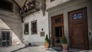 Une cour intérieure avec un sol en pierre, une porte en bois et un balcon orné de fleurs.