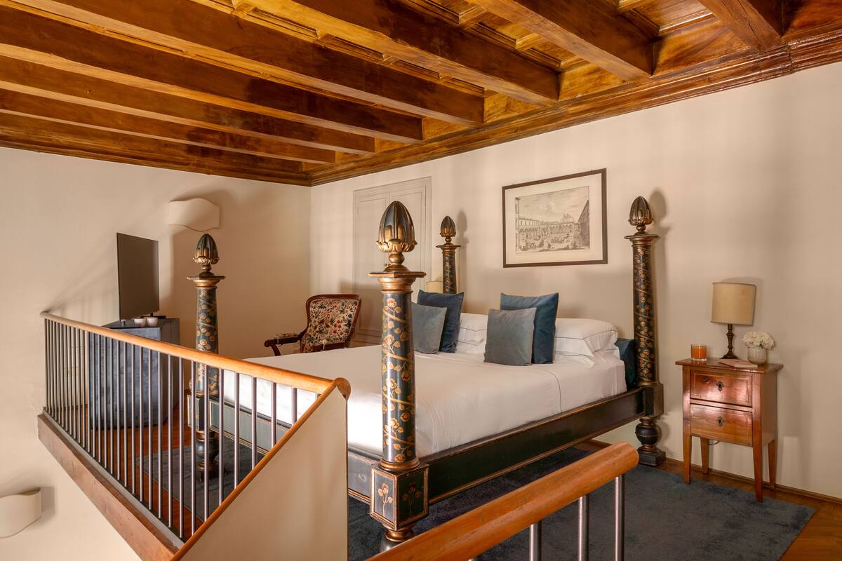 Une chambre à coucher avec un lit en bois, une table de chevet, une chaise et un escalier.