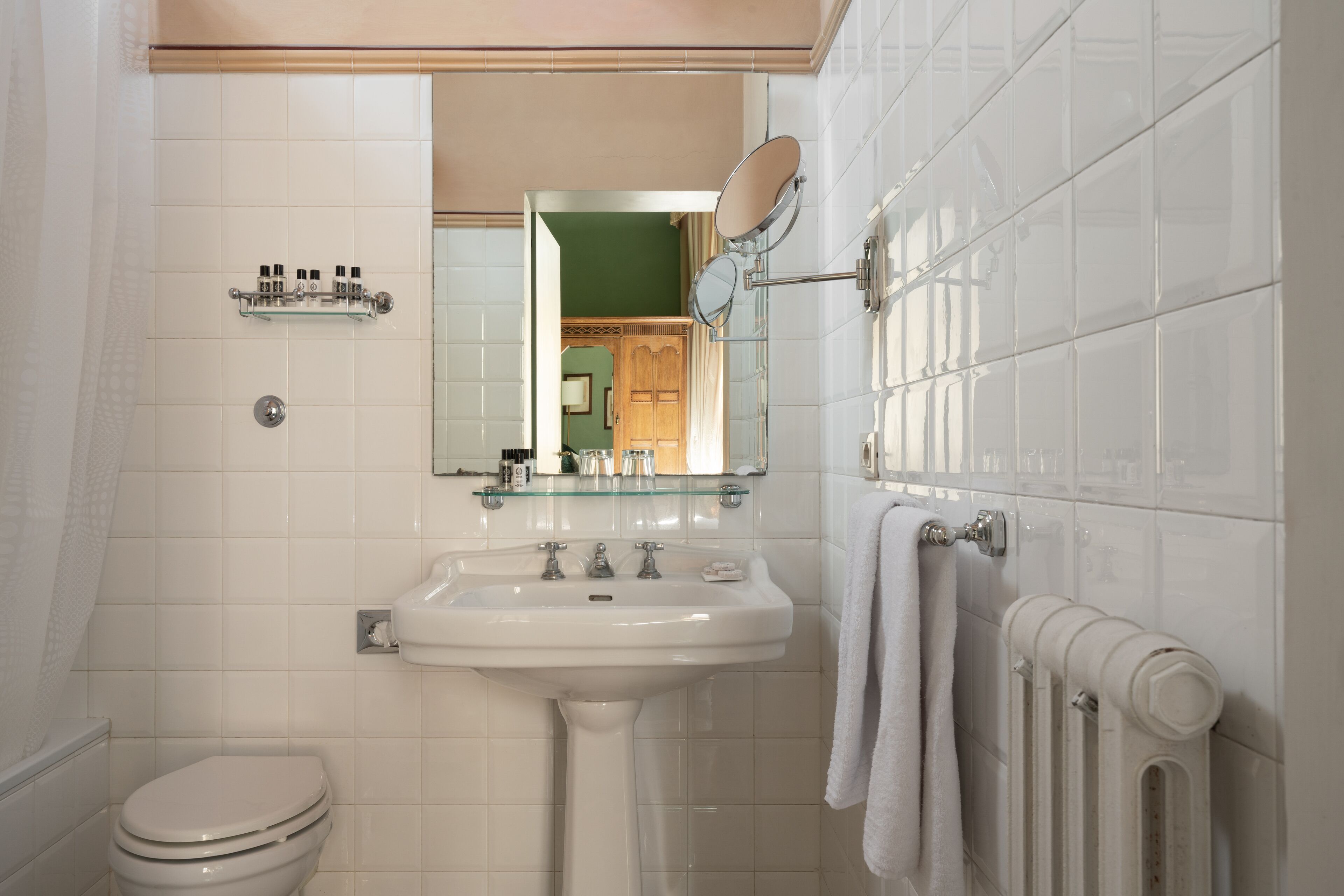 Une salle de bain avec un lavabo blanc, un miroir, des toilettes et un porte-serviettes.