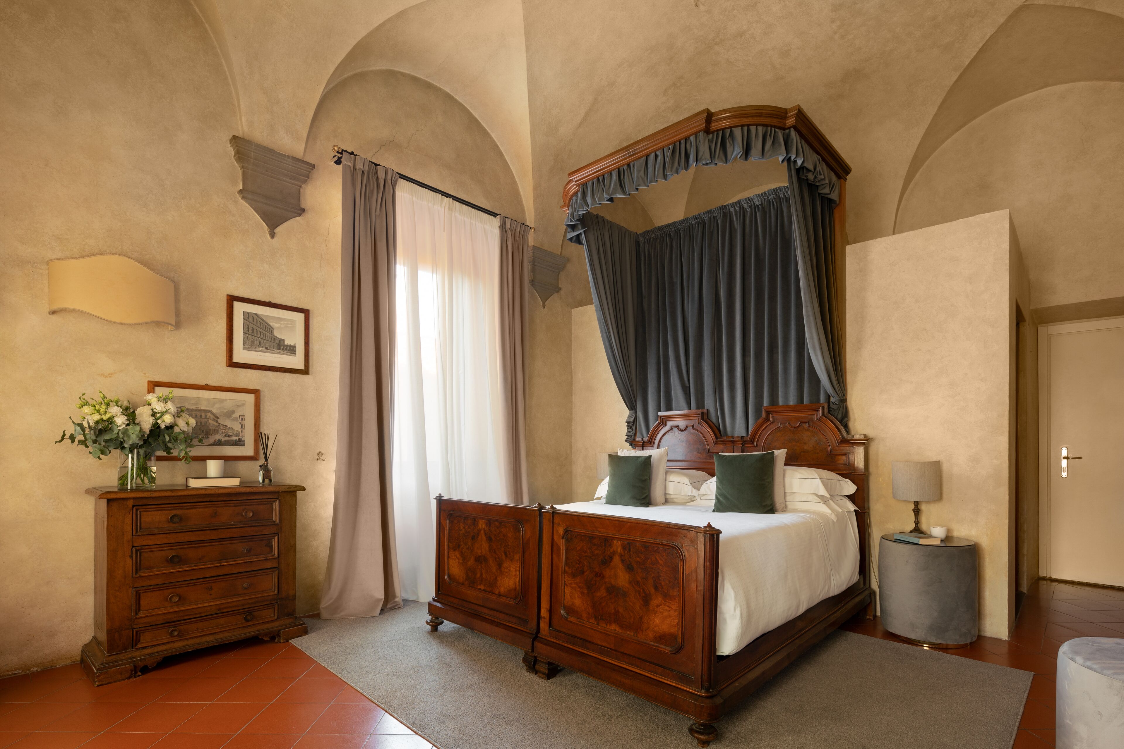 A bedroom with a four-poster bed, a dresser, a lamp, and a framed picture on the wall.