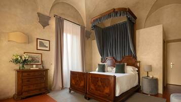 A bedroom with a four-poster bed, a dresser, a lamp, and a framed picture on the wall.