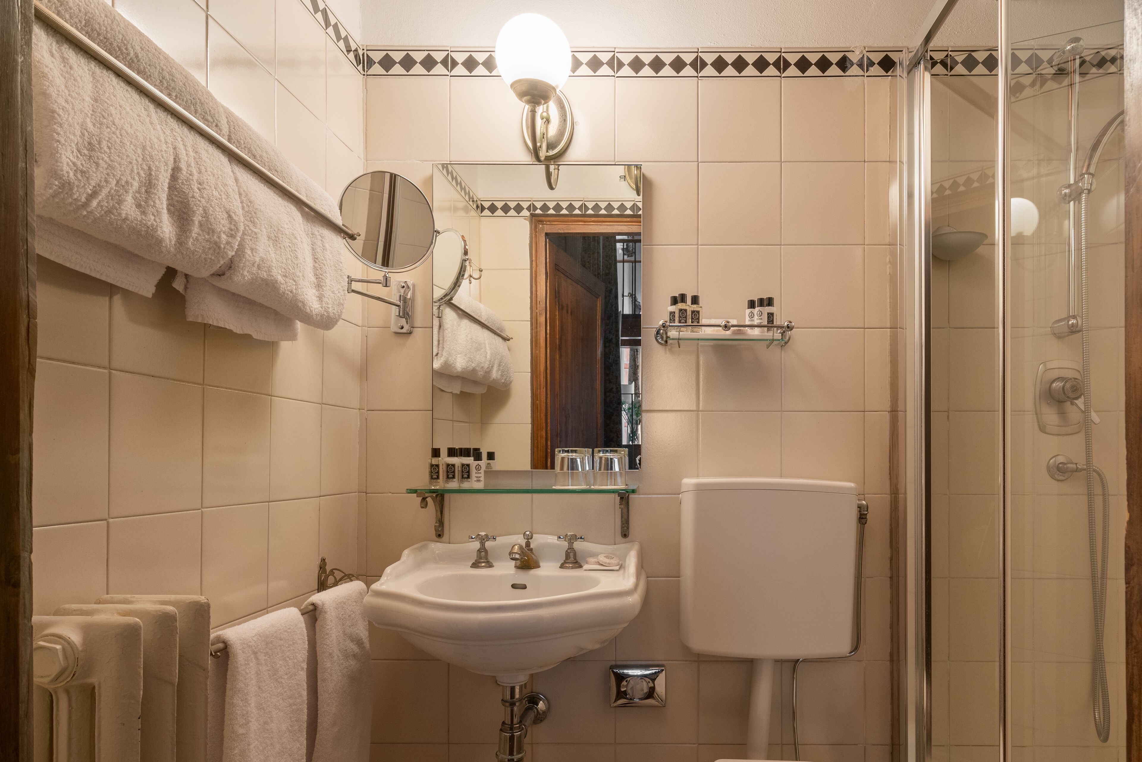 A bathroom with a white sink, mirror, towel rack, and glass shower enclosure.