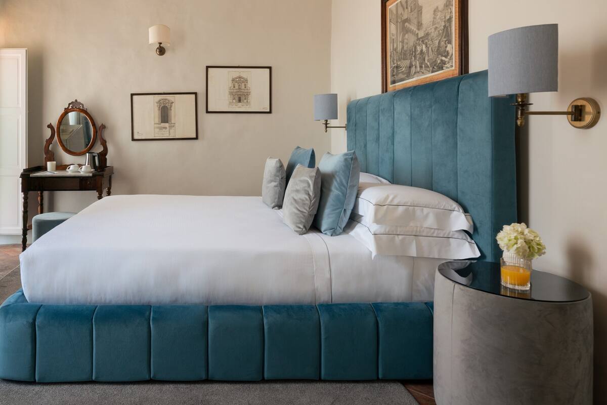 Une chambre à coucher avec un grand lit, une table de chevet, une lampe et des tableaux encadrés accrochés au mur.