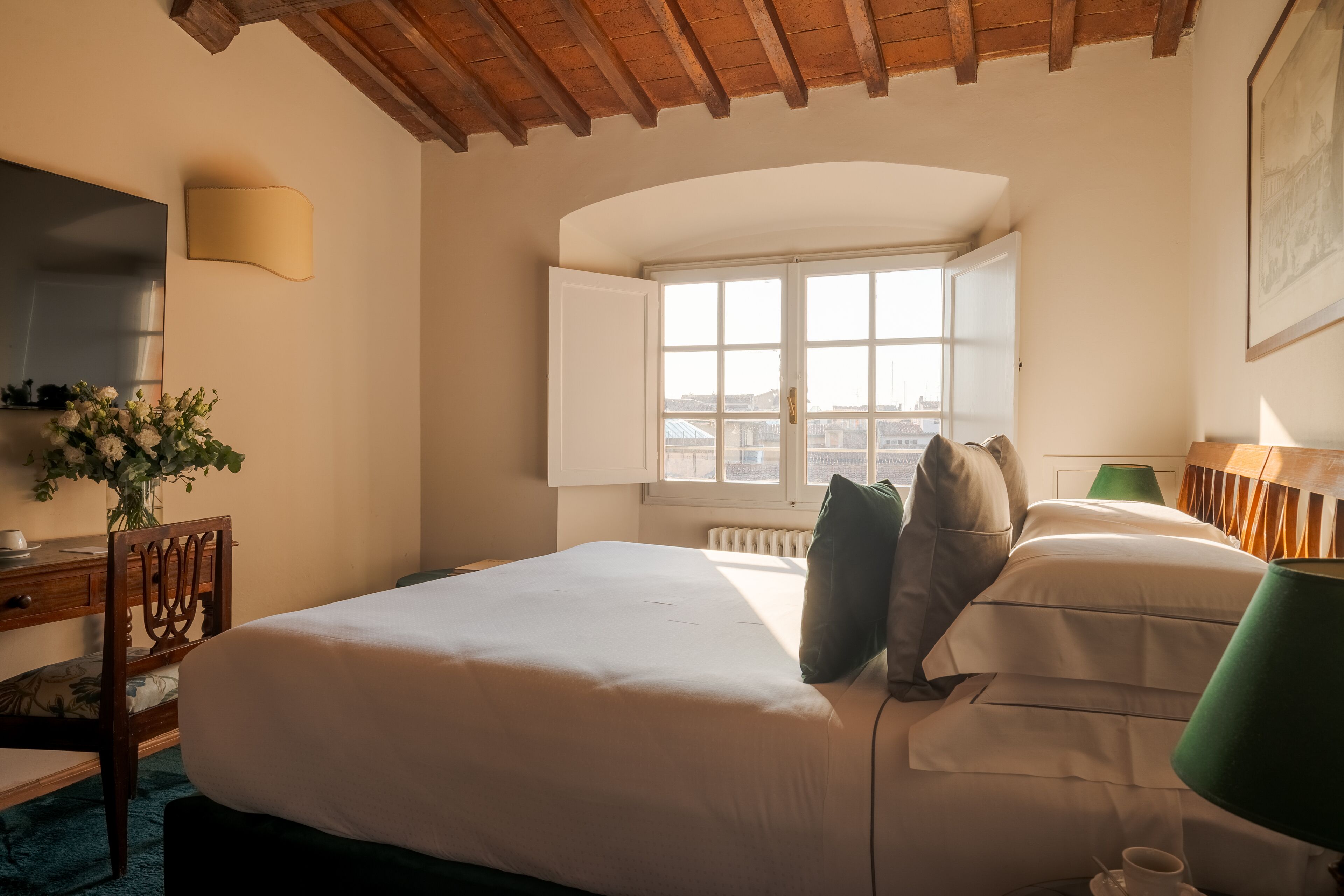 Habitació d'hotel amb un llit gran, un escriptori amb cadira, una finestra amb vistes i una làmpada.