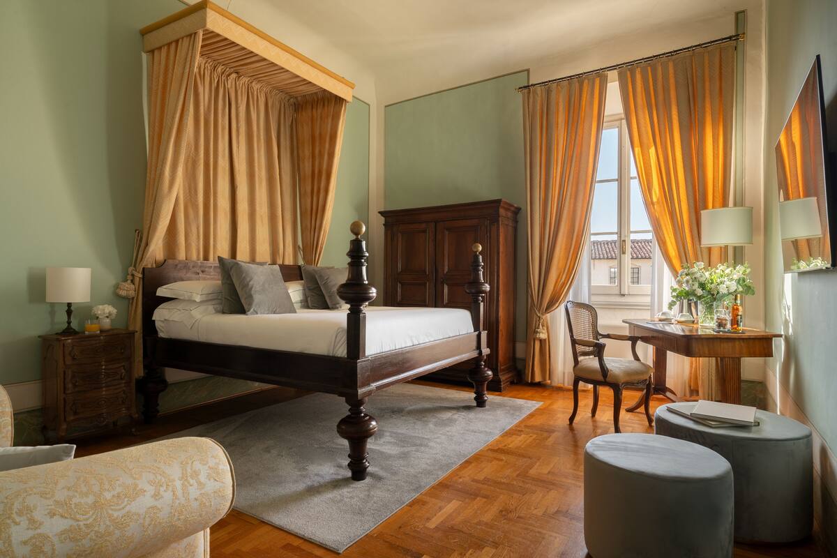 Un lit à baldaquin avec un cadre en bois, une armoire en bois, une petite table ronde avec une lampe et une chaise.
