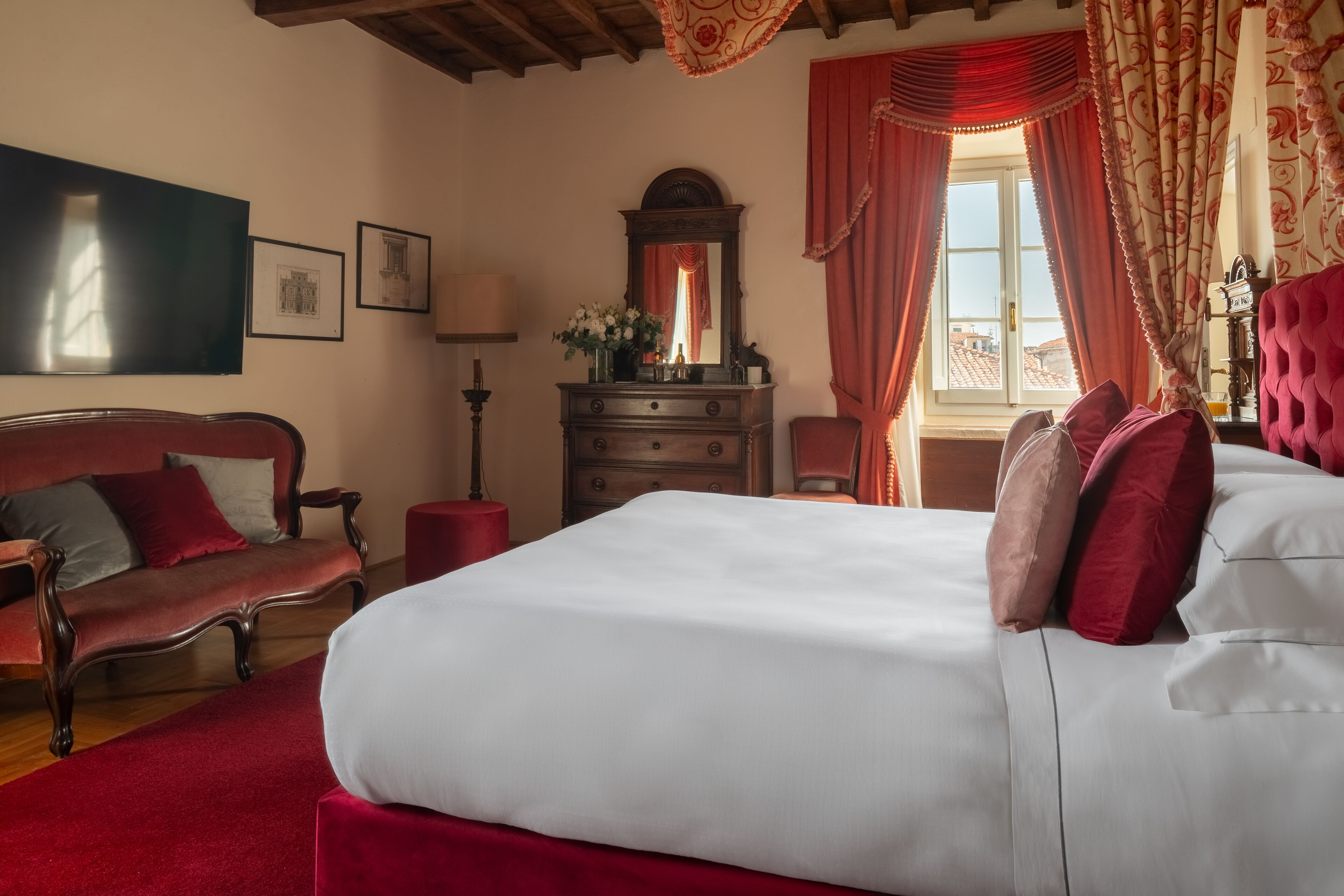 Un dormitorio con una cama grande, un aparador de madera, una silla y un sofá rojo.
