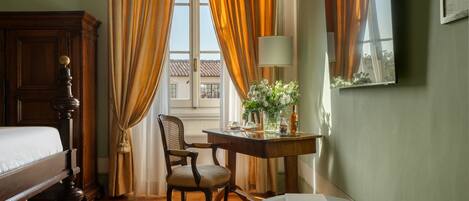 A bedroom with a wooden bed, a desk with a lamp, and a chair.