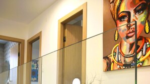 A modern interior with a glass railing, a wooden floor, a potted plant, and a colorful painting on the wall. - Three bedroom villa with pool (Malinska)