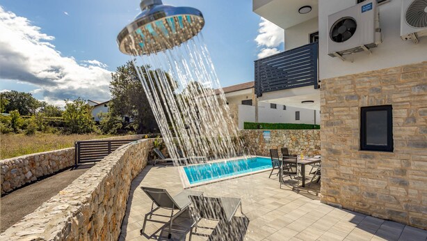 A rooftop pool area with a stone wall, outdoor furniture, and a water feature. - Three bedroom villa with pool (Malinska)