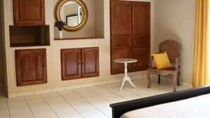A room with wooden cabinets, a mirror, a chair with a yellow pillow, and an air conditioning unit.