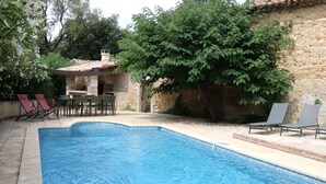 A swimming pool with lounge chairs and a stone building in the background.