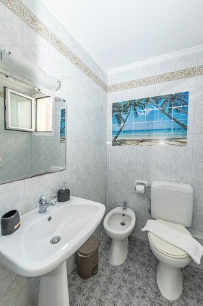 A bathroom with a sink, bidet, toilet, and a decorative tile backsplash. - Angel Luxury Apartment in Kriopigi (Kassandra)