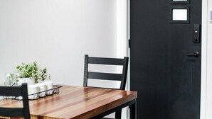 Ein Essbereich mit einem Holztisch und Stühlen, einer schwarzen Tür und einer weißen Wand.