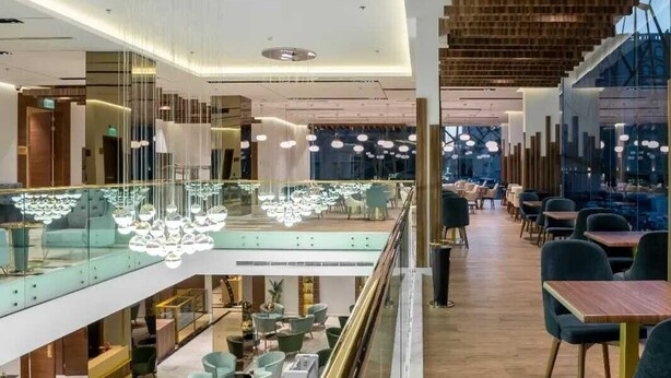 Un interior moderno con barandilla de vidrio, detalles de paneles de madera e iluminación contemporánea.