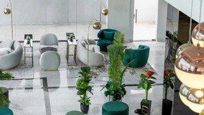 Una sala de estar moderna con suelo de mármol, sofás blancos y verdes, y varios otomanes verdes.