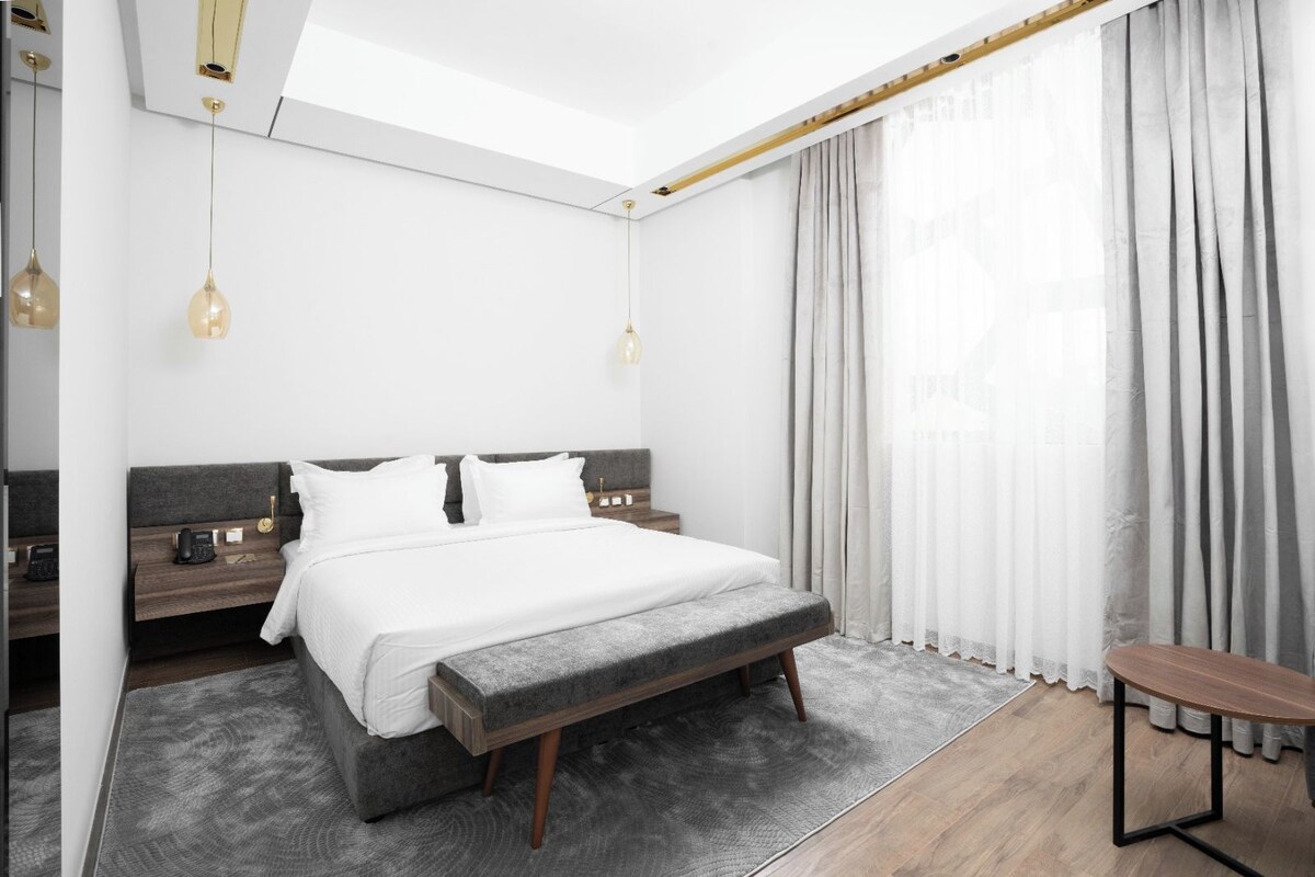 A modern bedroom with a bed, bedside tables, a bench, and a small table.
