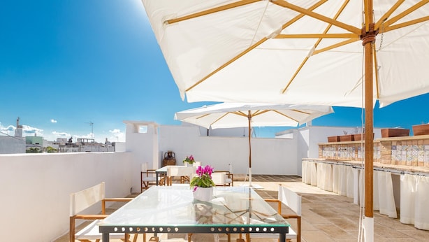 A rooftop terrace with a glass table, white chairs, and large umbrellas. - 3292 Terra Allisti - Casa 1 by Barbarhouse (Alliste)
