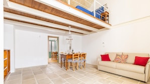 A spacious living area with a high ceiling, a dining table with chairs, a sofa with red cushions, and a staircase leading to an upper level. - 3292 Terra Allisti - Casa 1 by Barbarhouse (Alliste)