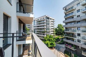 A multi-story residential building with balconies, a rooftop garden, and a clear view of the surrounding area. - RentPlanet Kępa Mieszczańska (Wroclaw)