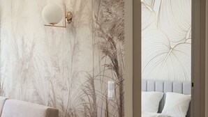 Una camera da letto moderna con un letto grande, un divano e una parete con carta da parati a tema natura.