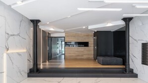 Una hall moderna con pavimento in marmo, una reception in legno e un'area salotto nera.