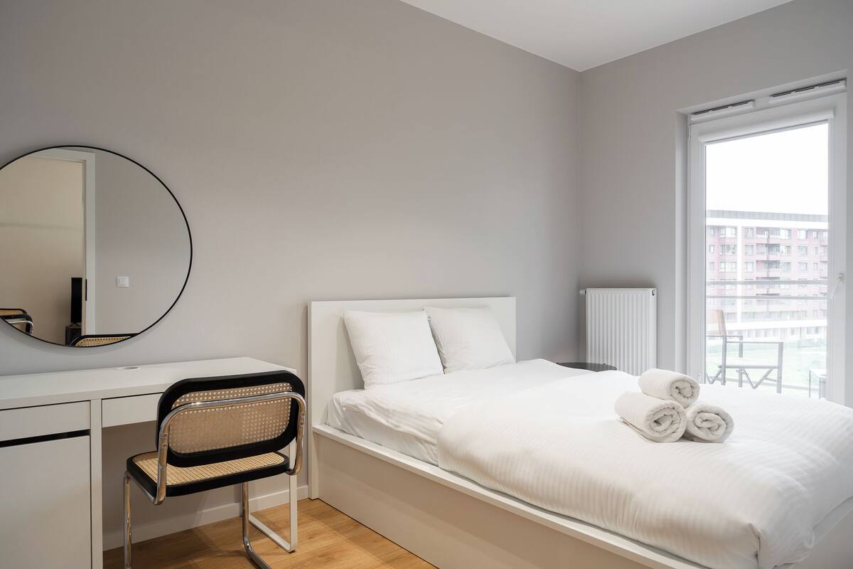 A modern bedroom with a bed, a desk, and a chair.