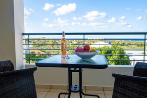 A balcony with a table, chairs, a bottle, and a bowl of fruit. - Wonderful Villa with Private Pool, Panoramic Sea Views & Spacious Interiors (Chania)