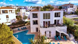 A two-story building with a swimming pool, multiple balconies, and outdoor seating areas. - Wonderful Villa with Private Pool, Panoramic Sea Views & Spacious Interiors (Chania)