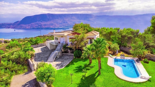 Une villa dotée d’une piscine, d’un escalier et offrant une vue sur la mer et les montagnes.