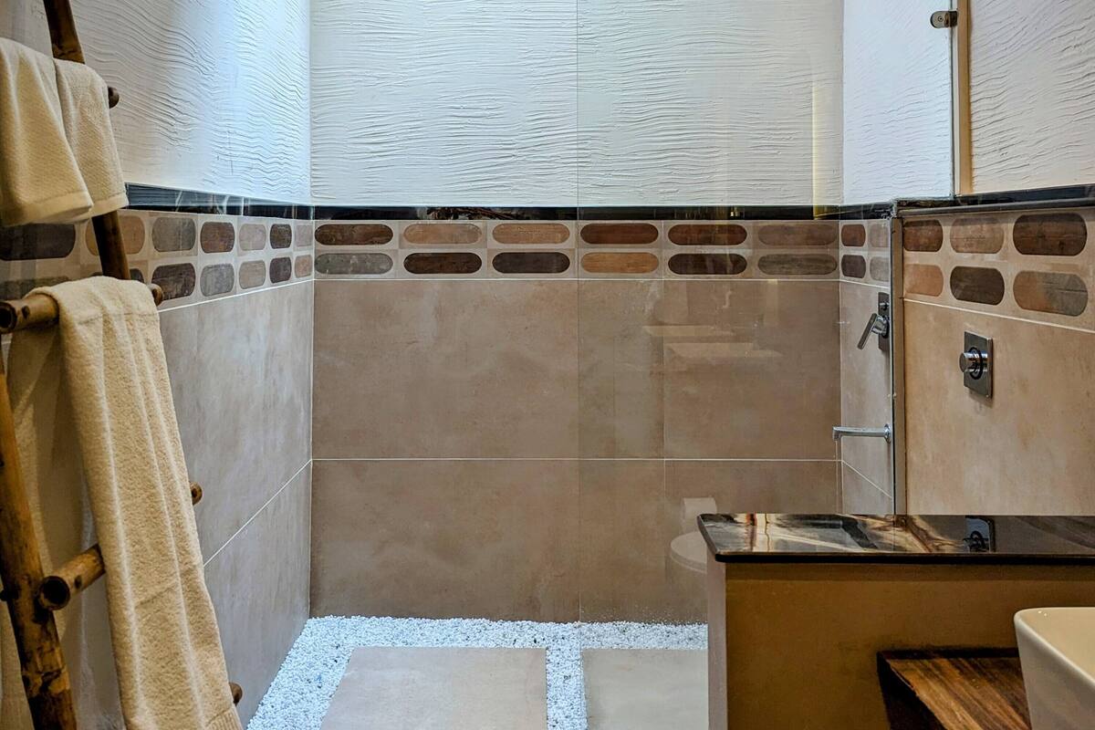 Un baño con ducha, inodoro, lavabo y toallero.