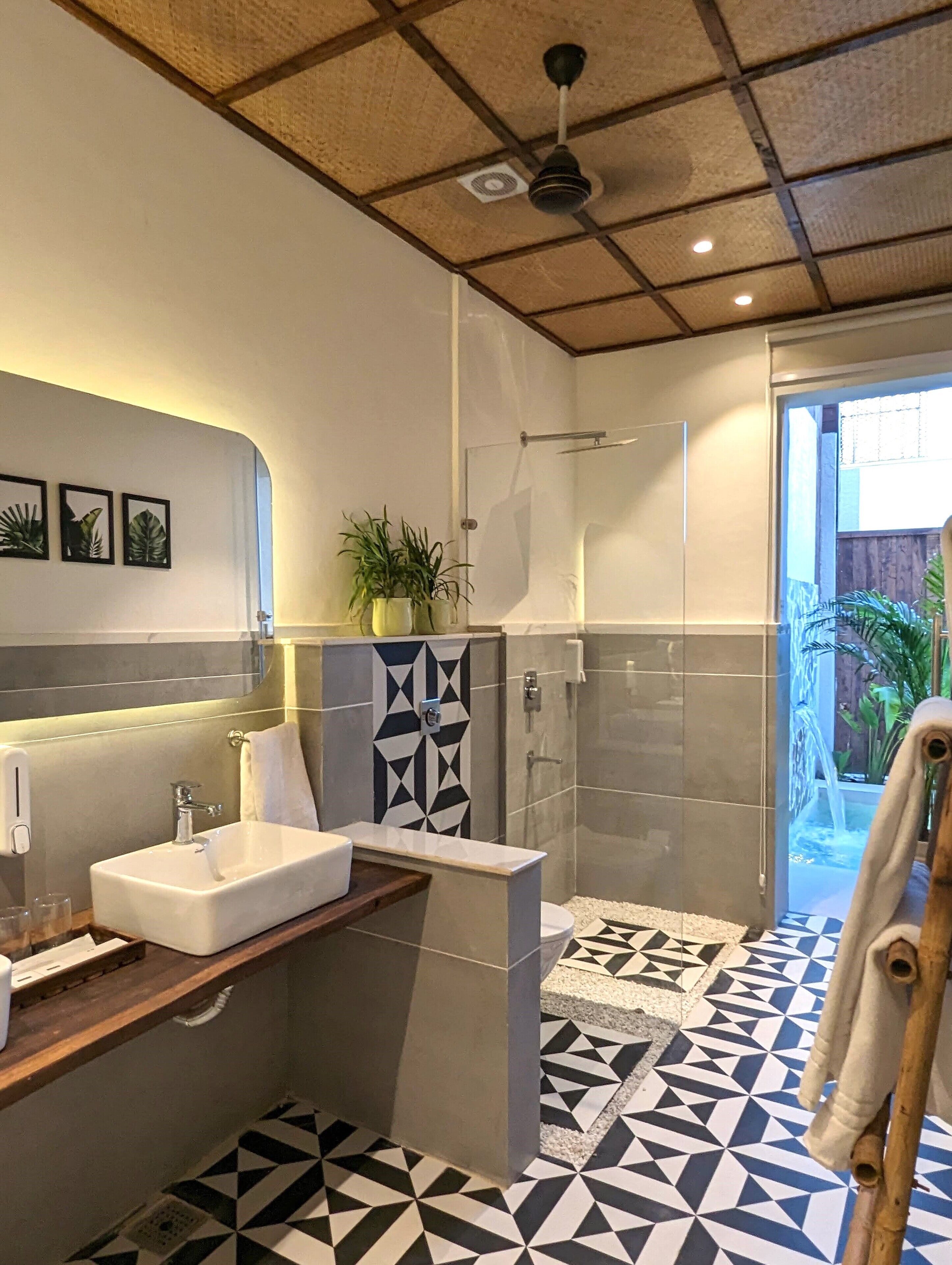 A modern bathroom with a large sink, shower, and a geometric patterned floor.