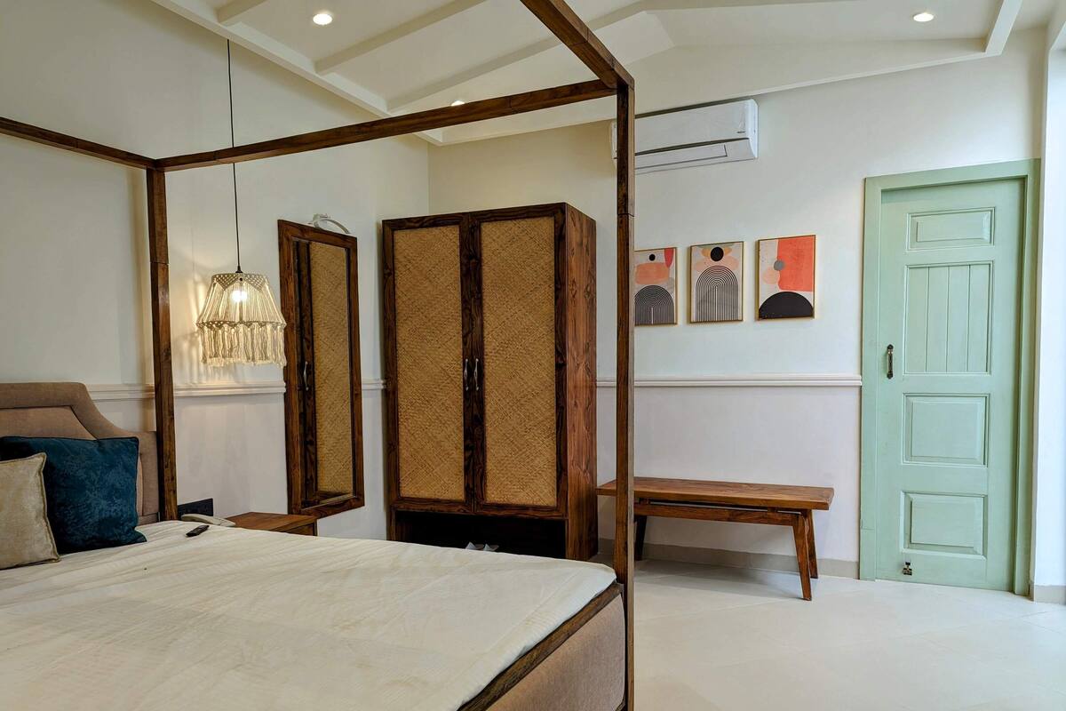 Un dormitorio con cama con dosel, armario de madera y una banca.