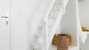 A white staircase with a handrail, a white door with a handle, and a small wicker basket on the landing. - Seaclusion (Santorini)