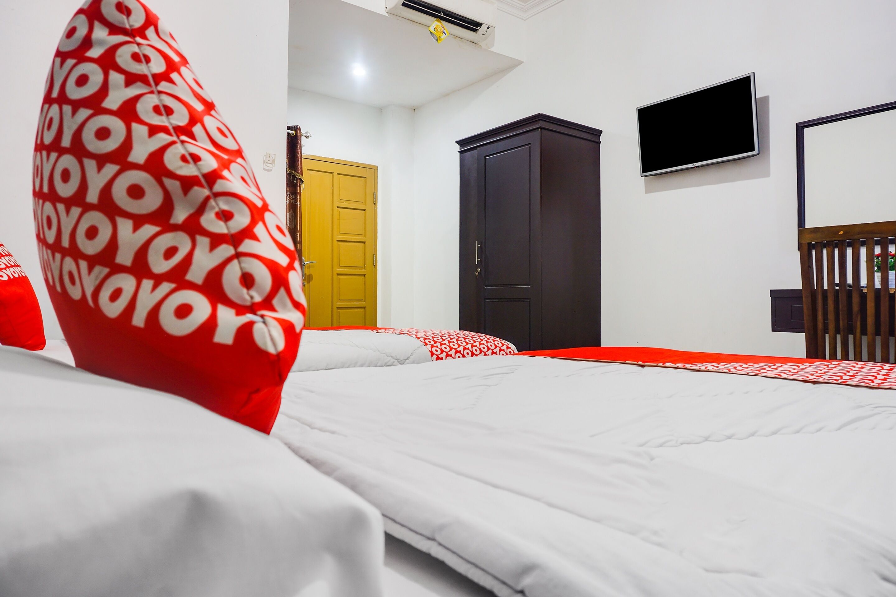 A hotel room with a bed, a wardrobe, a television, and a door.