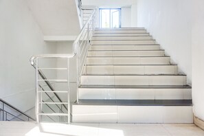 Un escalier avec des rampes et une main courante en métal, menant à l’étage supérieur.