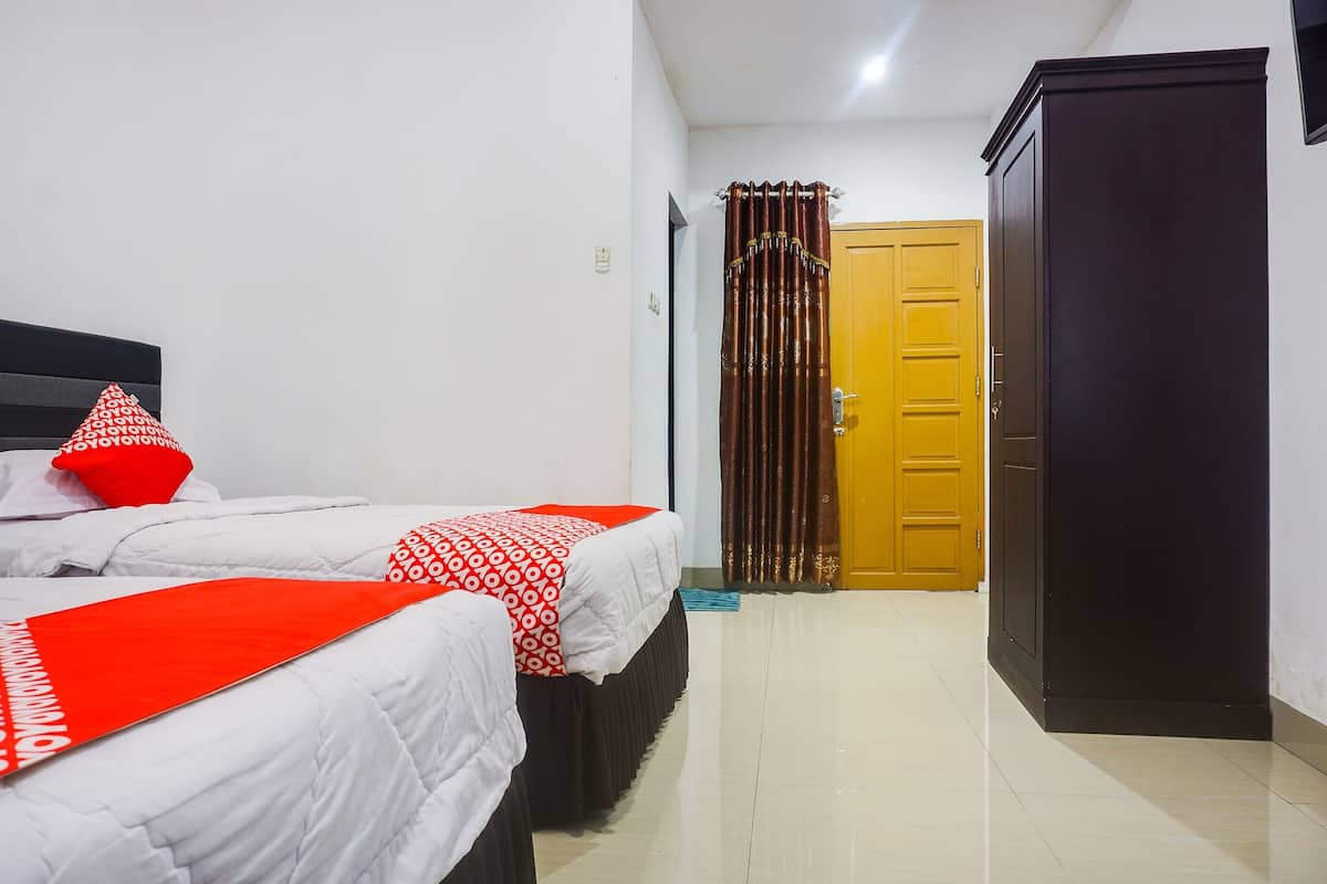 Una habitación de hotel con dos camas, un armario y una puerta.
