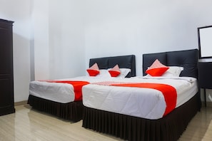 A hotel room with two beds, each with a black headboard, white bedding, and red accents.