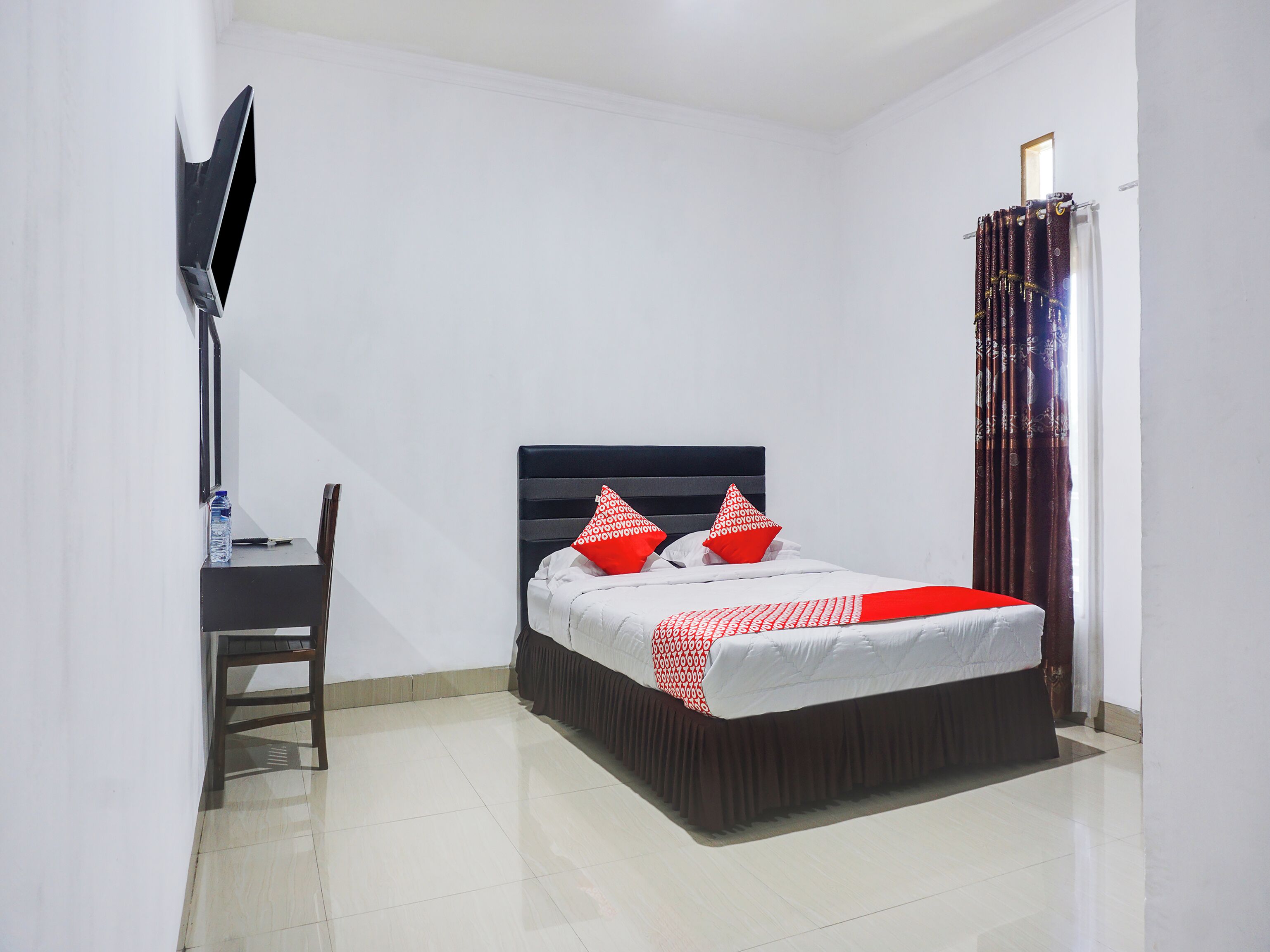 A bedroom with a bed, a desk, and a TV.