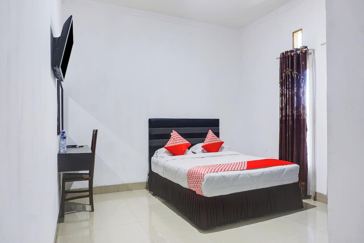 Un dormitorio con cama, escritorio y televisor.