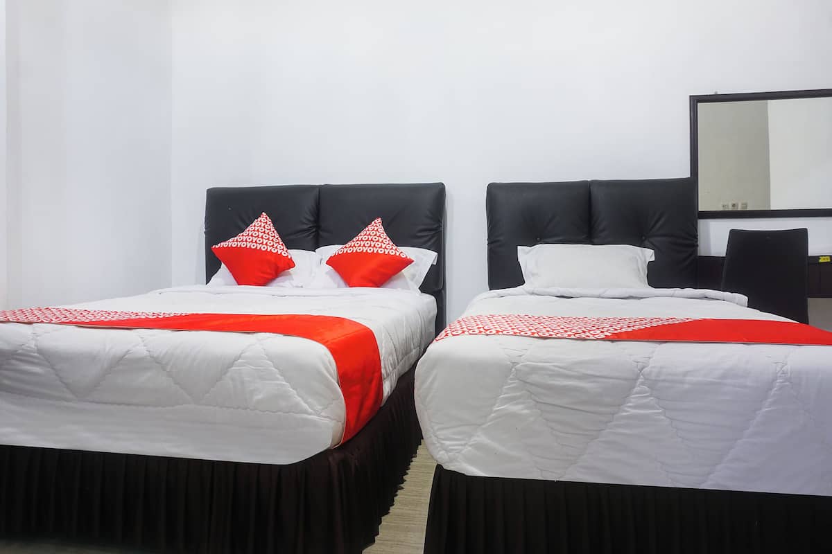 Two single beds with black headboards and white bedding, a black chair, and a mirror on the wall.